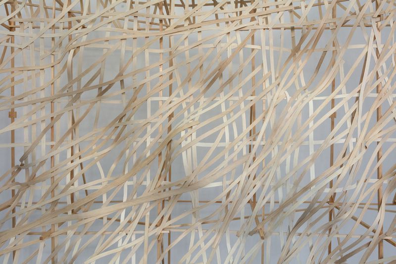A woven flat reed installation by Stephen Talasnik inside the Architektur Galerie Berlin, viewed through the gallery window.